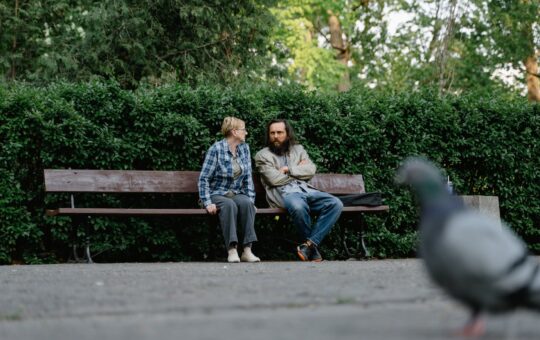 an elderly people sitting on a wooden bench while having conversation